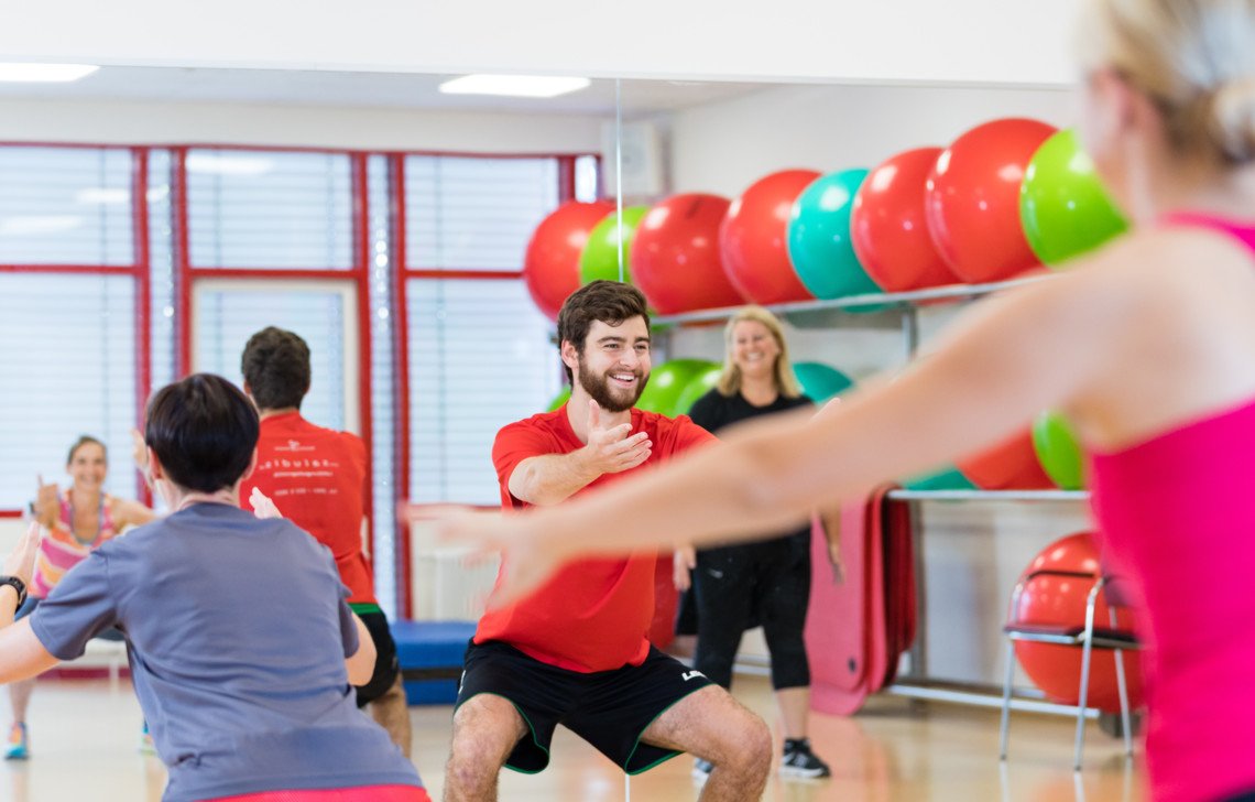 Sportgruppe mit Physiotherapeut machen Kniebeugen